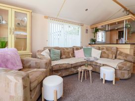A living room with a sofa and display cabinet at 152 Central Park in Prestatyn