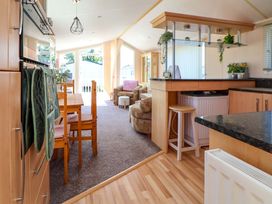 A living room and kitchen area with a table and chairs at 152 Central Park Prestatyn