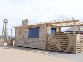 A wooden building with signage and a pergola at 152 Central Park in Prestatyn
