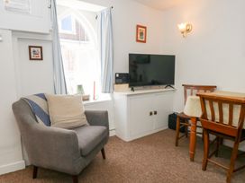 A living room with an armchair and television at Driftwood in Weymouth