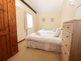 A bedroom with two single beds with pillows and towel rolls beside a wooden chest of drawers and a window at Beechwood in Wood Norton near Foulsham
