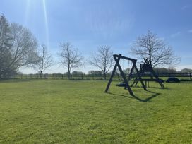 A swing set and slide on grass at Beechwood in Wood Norton near Foulsham