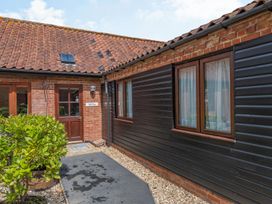 An outdoor entryway with a wooden door and two windows on a building with brick and wooden siding at Willow Wood Norton near Foulsham