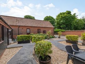 An outdoor courtyard with paved walkways shrubs and chairs near a brick building at Willow Wood Norton near Foulsham