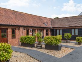 An outdoor courtyard with a gravel ground and paved walkways surrounded by bushes and shrubs in planter boxes at Willow Wood Norton near Foulsham