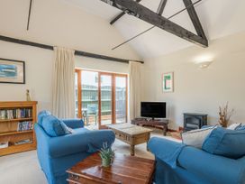 A living room with blue sofas a wooden coffee table a television and a bookcase at Willow in Wood Norton near Foulsham