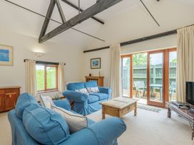 A living room with blue sofas wooden tables and glass doors leading to a patio at Willow in Wood Norton near Foulsham