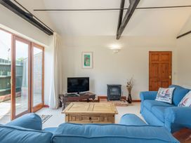A living room with blue sofas a wooden coffee table a TV and a wood burning stove at Willow in Wood Norton near Foulsham