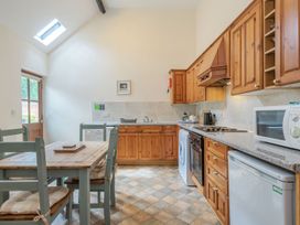 A kitchen with wooden cabinets dining table and chairs a dishwasher oven microwave and refrigerator at Willow Wood Norton near Foulsham