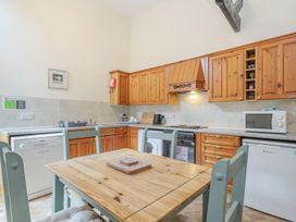 A kitchen with wooden cabinets a dining table four chairs dishwasher microwave and small refrigerator at Willow in Wood Norton near Foulsham