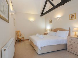 A bedroom with a double bed wooden side tables lamps a wooden chair and wall art at Willow Wood Norton near Foulsham