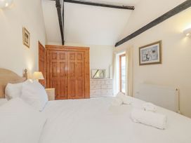 A bedroom with a wooden wardrobe a dresser with mirror and a bed with white linens at Willow Wood Norton near Foulsham