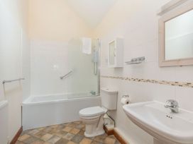 A bathroom with a bathtub shower combination toilet sink mirror and tiled flooring at Willow in Wood Norton near Foulsham