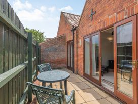 An outdoor patio with a round table and two chairs next to a brick building with glass doors at Willow in Wood Norton near Foulsham