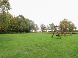 A garden with a swing set and grass at Willow Wood Norton near Foulsham