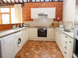 A kitchen with white cabinets tiled floor and brick walls at Pear Tree in Wood Norton