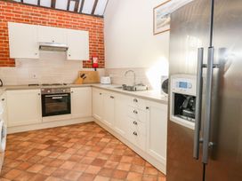 A kitchen with a stainless steel refrigerator oven stove white cabinets and a tiled floor at Pear Tree in Wood Norton