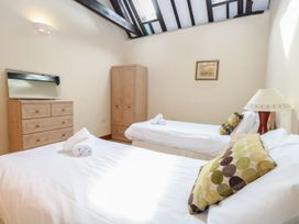 A bedroom with two single beds with pillows and towels a dresser with a mirror a wardrobe and a lamp at Pear Tree in Wood Norton