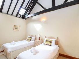 A bedroom with two single beds and a nightstand with a lamp at Pear Tree in Wood Norton