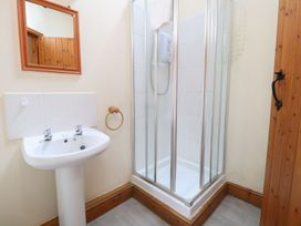 A bathroom with a pedestal sink a mirror and a corner shower with glass doors at Pear Tree in Wood Norton