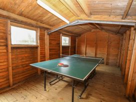 A wooden room with a ping pong table and paddles at Pear Tree in Wood Norton