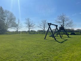A play structure and swing set in a grassy area at Pear Tree Wood Norton