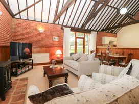 A living room with a television a sofa and a dining area at Pear Tree in Wood Norton