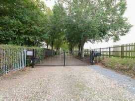 A gated entrance with trees lining the path at Pear Tree in Wood Norton