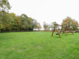 An outdoor area with a swing set and tire swing at Pear Tree in Wood Norton