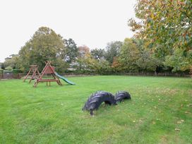 An outdoor play area with a slide and tire at Pear Tree in Wood Norton
