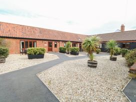 An outdoor courtyard with gravel, potted plants, and a paved walkway at Holly Berry Wood Norton near Foulsham