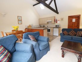 A living room with blue sofas and a wooden coffee table next to a kitchen and dining area at Holly Berry Wood Norton near Foulsham
