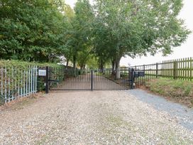 A pathway with a gate and trees at Holly Berry in Wood Norton near Foulsham