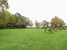 An outdoor space with swing set and trees at Holly Berry in Wood Norton near Foulsham