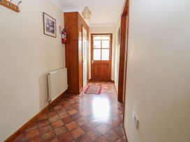 A hallway with tiled floor a wooden door a fire extinguisher and a radiator at Sycamore in Wood Norton near Foulsham