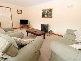 A living room with two green sofas a wooden coffee table a TV on a stand and a fireplace at Sycamore in Wood Norton near Foulsham
