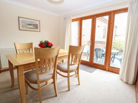 A dining room with wooden table and chairs and glass doors leading outside at Sycamore Wood Norton near Foulsham