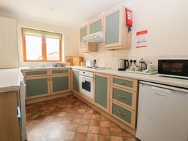 A kitchen with green and wood cabinets a window a stove a microwave and various kitchen appliances at Sycamore in Wood Norton near Foulsham