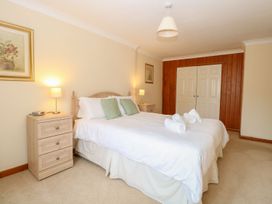 A bedroom with a double bed white bedding and two green pillows beside two bedside tables with lamps and a wooden wardrobe at Sycamore Wood Norton near Foulsham