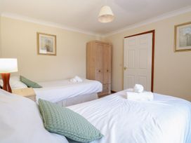 A bedroom with two single beds pillows and rolled towels on the beds a wooden wardrobe and framed pictures on the walls at Sycamore Wood Norton near Foulsham