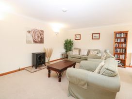 A living room with a stove and bookshelf at Sycamore, Wood Norton near Foulsham