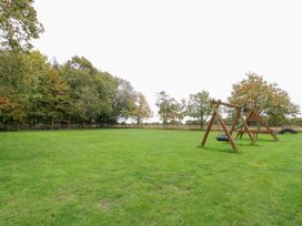 A garden with a swing set and trees at Sycamore, Wood Norton near Foulsham