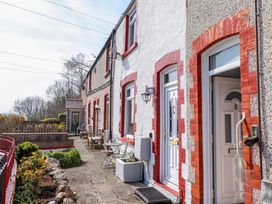 A row of terraced houses with white doors and red brick edging a garden with plants at 4 Bay View Terrace in Llandudno