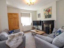 A living room with two gray sofas a wooden coffee table a dark fireplace a television and artwork on the walls at 4 Bay View Terrace in Llandudno