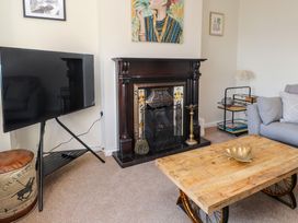 A living room with a wooden coffee table on wheels a dark wood fireplace a grey sofa and a flat screen tv at 4 Bay View Terrace in Llandudno
