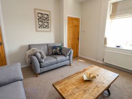 A living room with two gray sofas a wooden coffee table and a framed artwork on the wall at 4 Bay View Terrace in Llandudno