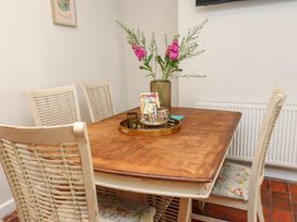 A dining table with a vase of flowers and chairs with floral cushions at 4 Bay View Terrace in Llandudno