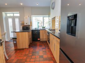 A kitchen with wooden cabinets a black countertop a stainless steel refrigerator a microwave and a window at 4 Bay View Terrace in Llandudno