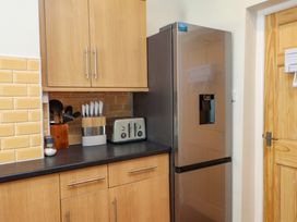A kitchen corner with wooden cabinets a stainless steel refrigerator a toaster a knife block and utensils on the counter at 4 Bay View Terrace in Llandudno