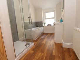 A bathroom with a shower enclosure bathtub sink and window at 4 Bay View Terrace in Llandudno